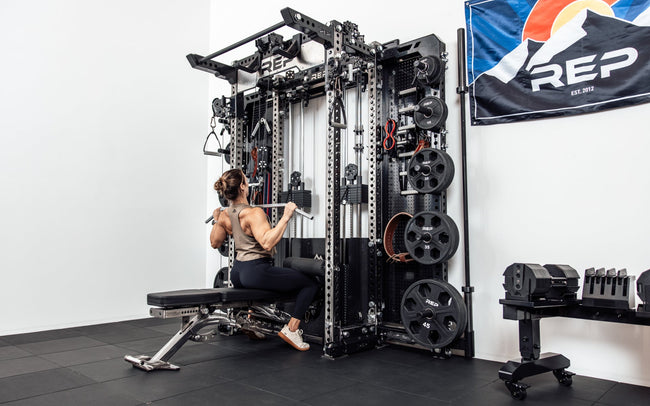 An athlete performing a lat pulldown on the Wall-Mounted Ares™ 2.0 while seated on a REP BlackWing™ bench