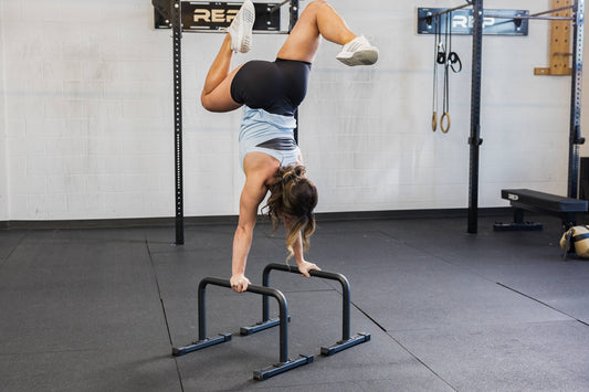 Athlete holds a handstand with REP® paralletes.